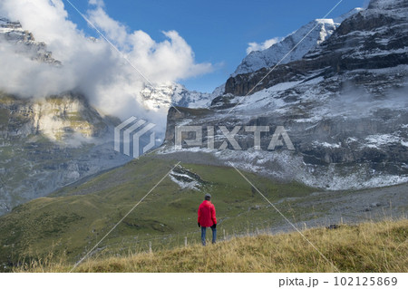 Sporty woman standing in front of snow mountains and enjoying view of Switzerland nature. Wanderlust, sport, beauty in nature. 102125869