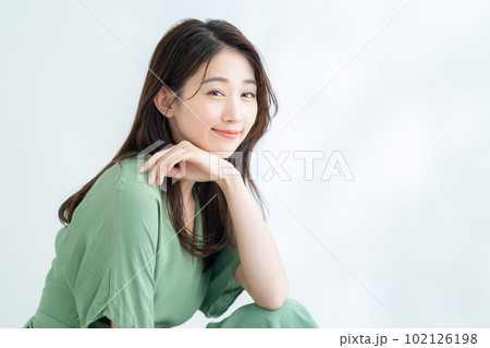 木漏れ日の白バックでスキンケアをする若い女性 木漏れ日の白バックでスキンケアをする若い女性 102126198
