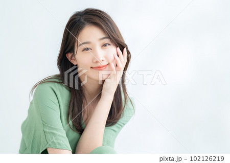 木漏れ日の白バックでスキンケアをする若い女性 木漏れ日の白バックでスキンケアをする若い女性 102126219