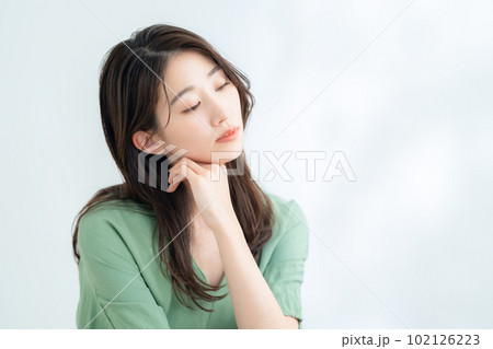 木漏れ日の白バックでスキンケアをする若い女性 102126223