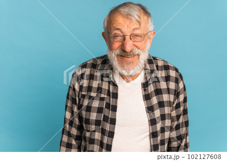 Portrait retired old man with white hair and beard laughter excited over blue color background Portrait retired old man with white hair and beard laughter excited over blue color background 102127608