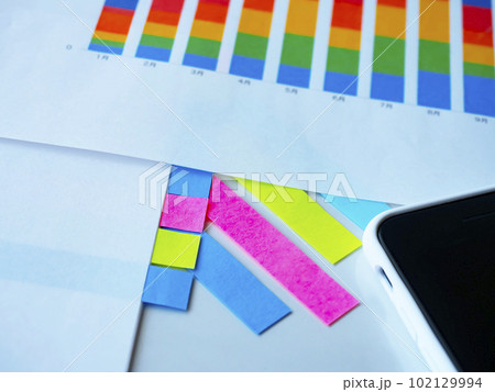 テーブルに置かれたグラフ、書類とスマートフォン テーブルに置かれたグラフ、書類とスマートフォン 102129994