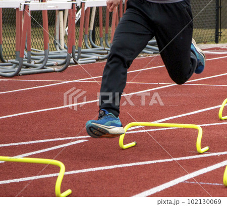Legs of a runner in the air over yellow mini hurdles Legs of a runner in the air over yellow mini hurdles 102130069