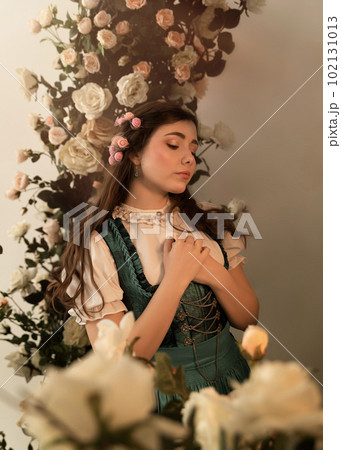 A young peasant woman standing in a garden with flowers dressed in a 19th century bavarian dress. 102131013