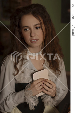 Beautiful woman in vintage clothes reading a letter in an art studio Beautiful woman in vintage clothes reading a letter in an art studio 102132278