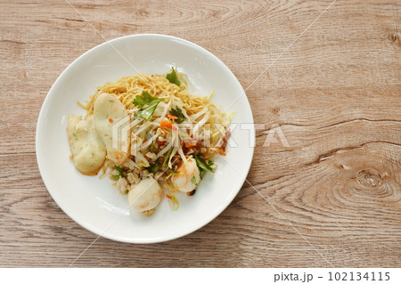 dry Chinese yellow egg noodles topping boiled chop pork and ball on plate 102134115