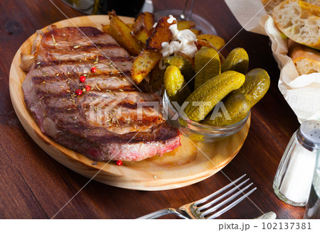 Appetizing beef entrecote with boiled potatoes and pickled cucumbers 102137381
