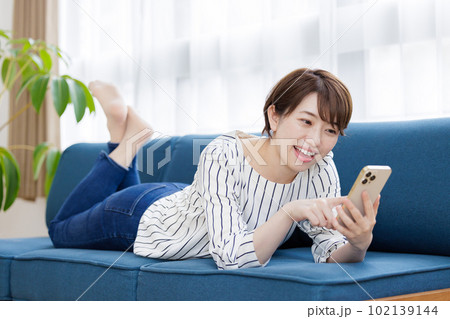 ソファでスマホを操作する女性 102139144