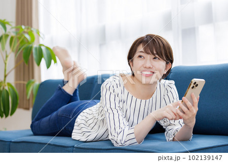 ソファでスマホを操作する女性 102139147