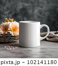 Coffee mug, a white cup on a table with a cupcake and flowers. Styled photo, product mockup 102141180