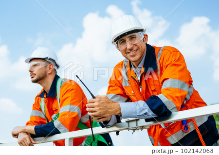 Professional engineers technicians working at wind turbine farm field 102142068