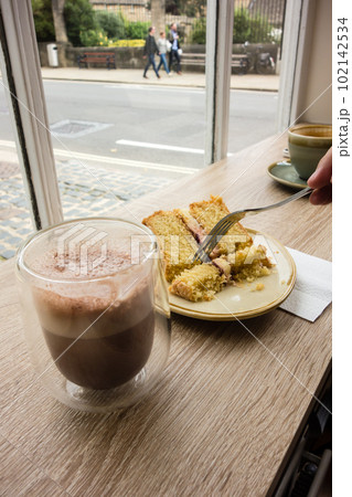 カフェの窓際のテーブルに置かれたコーヒーとケーキ　イギリスオックスフォードの街並み 102142534