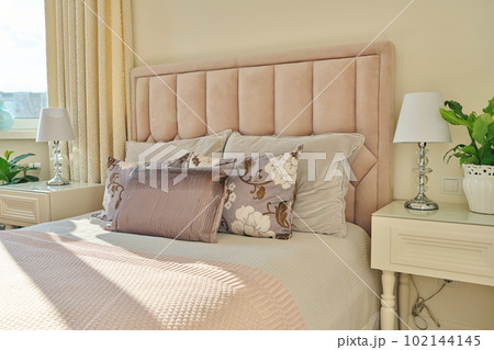 Classic bedroom interior in light ivory colors, in warm sunlight 102144145