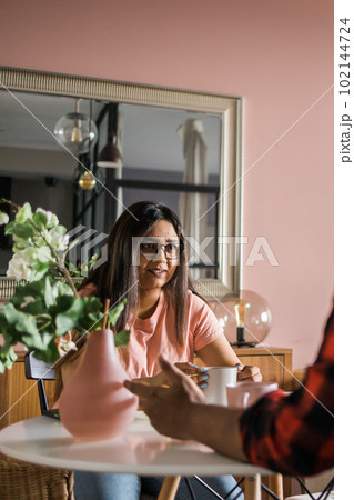 Happy couple eating breakfast and talking at dining table in morning. Indian girl and latino guy. Relationship and diversity concept 102144724