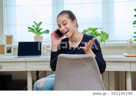 Cheerful teenage girl talking on phone at home Cheerful teenage girl talking on phone at home 102145290