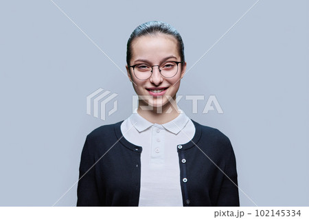 Close-up portrait of happy high school student girl on grey background 102145334