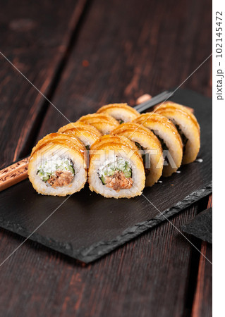 Sushi roll with smoked tuna with cucumber and cheese close-up. Traditional delicious fresh sushi roll set. Sushi menu. Japanese cuisine restaurant. Asian food Sushi roll with smoked tuna with cucumber and cheese close-up. Traditional delicious fresh sushi roll set. Sushi menu. Japanese cuisine restaurant. Asian food 102145472