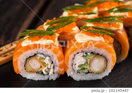 Sushi roll philadelphia with crab and cucumber and cream cheese, caviar on black background close-up. Sushi menu. Japanese food concept Sushi roll philadelphia with crab and cucumber and cream cheese, caviar on black background close-up. Sushi menu. Japanese food concept 102145487