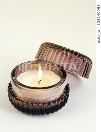 A burning scented candle in a brown glass jar on a white background A burning scented candle in a brown glass jar on a white background 102149093