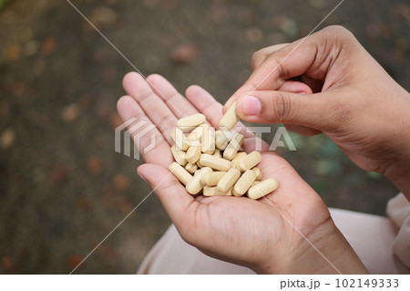 rear view of women hand taking medical tablet rear view of women hand taking medical tablet 102149333