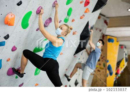 Female mountaineer protective mask climbing artificial rock wall without belay indoors 102153037