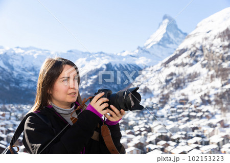 Woman photographer capturing mountain views in Swiss Alps in winter Woman photographer capturing mountain views in Swiss Alps in winter 102153223