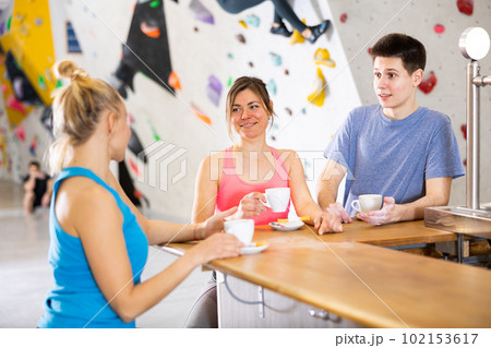 Young man and two women having conversation at bar counter in climbing center 102153617