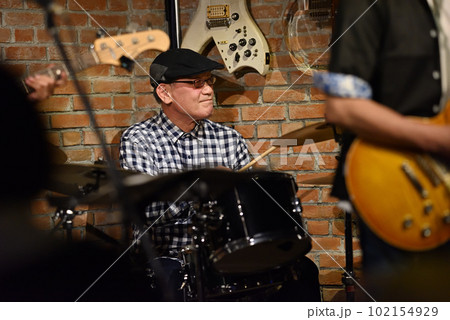 ライブハウスで演奏中のブルースバンドのドラマー 102154929