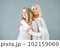Portrait of young blonde women friends in sportswear on background of grey wall 102159060
