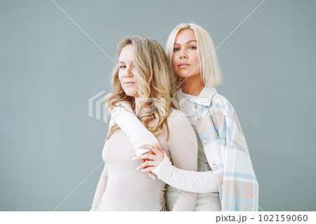 Portrait of young blonde women friends in sportswear on background of grey wall 102159060