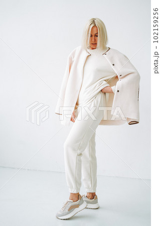 Full length portrait of smiling young blonde woman in sportswear on background of white wall 102159256