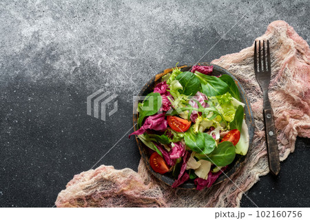 Green vegan salad of radicchio lettuce, frieze, arugula and spinach on a black background. Healthy food. View from above. 102160756