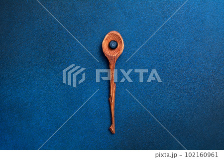 Fresh blueberry in a wooden spoon. Berry on a blue background. View from above. Fresh blueberry in a wooden spoon. Berry on a blue background. View from above. 102160961