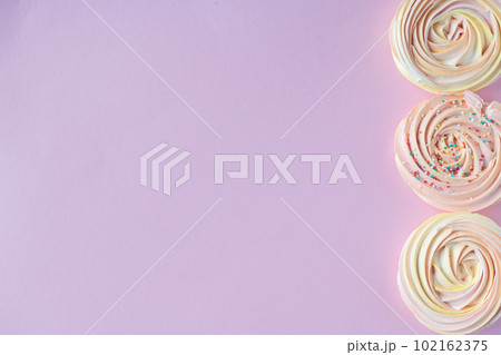 Pink round sweet meringues with decor lie on a pink background on the side 102162375