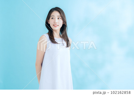 日差しが差し込むブルーバックでスキンケアをする若い女性 日差しが差し込むブルーバックでスキンケアをする若い女性 102162858