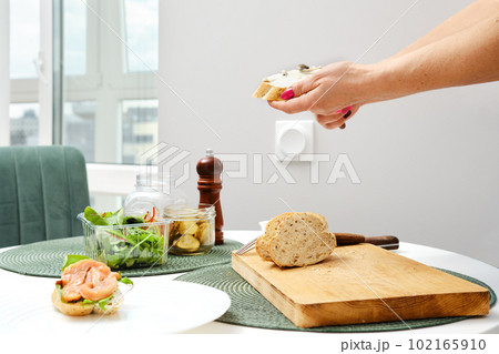 Hands of unrecognizable woman spreading ricotta on sandwich 102165910