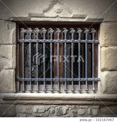 metal grating on an old window in a stone building 102167067