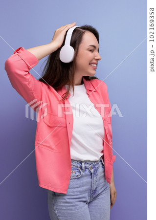 optimistic dancing brunette young woman in a shirt and jeans listens to her favorite music on 102169358