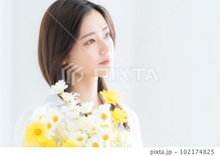 リビングで花束を持つ若い女性 102174825