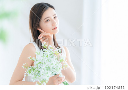 リビングで花束を持つ若い女性 102174851