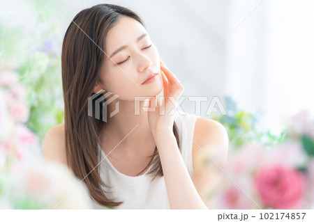 花に囲まれてスキンケアをする若い女性 花に囲まれてスキンケアをする若い女性 102174857