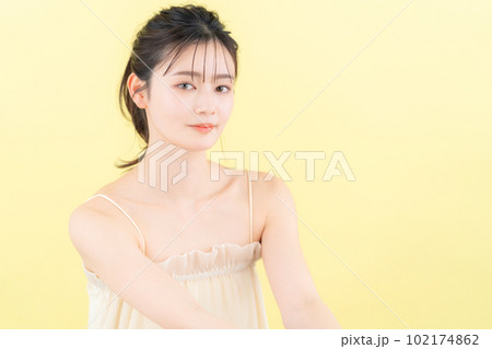 イエローバックでスキンケアをする若い女性 102174862