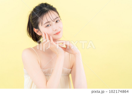 イエローバックでスキンケアをする若い女性 102174864