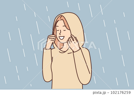 Happy woman enjoys autumn rain standing in autumn raincoat with hood that protects against drops 102176259