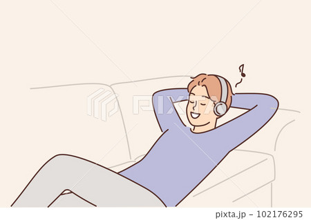 Man listens to music lying on couch with headphones and enjoys cool audio sound of favorite track Man listens to music lying on couch with headphones and enjoys cool audio sound of favorite track 102176295