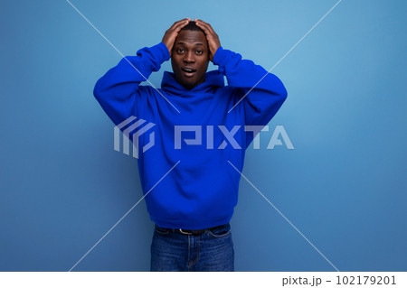 close-up of an upset black american man in a sweatshirt with a hood on a studio background with copy 102179201