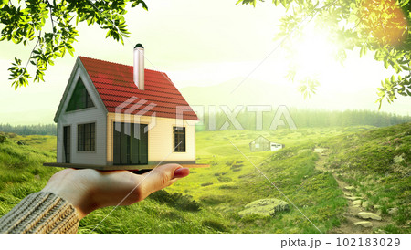 Female holding small 3D model of nice house over green field, nature background on sunny summer day. Buying new home Female holding small 3D model of nice house over green field, nature background on sunny summer day. Buying new home 102183029