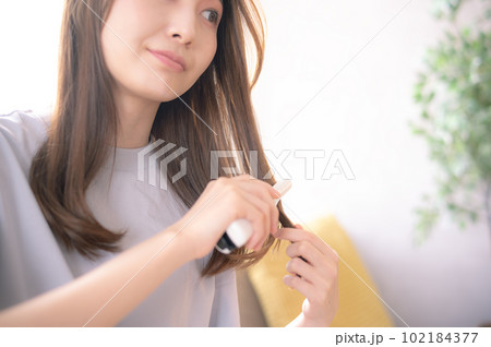 ヘアアイロンで髪の毛のお手入れをする女性 102184377