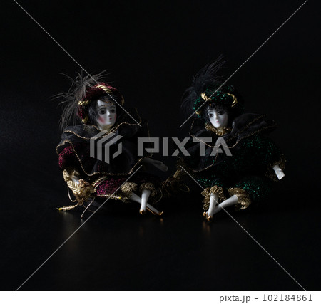 Porcelain doll, realistic vintage toys with grey eyes. The dolls are dressed in a carnival outfit, decorated with gold, harlequin, space for text	 102184861
