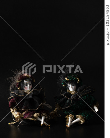 Porcelain doll, realistic vintage toys with grey eyes. The dolls are dressed in a carnival outfit, decorated with gold, harlequin, space for text Porcelain doll, realistic vintage toys with grey eyes. The dolls are dressed in a carnival outfit, decorated with gold, harlequin, space for text 102184863